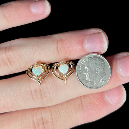 A pair of heart shaped, yellow gold opal stud earrings.  The top of the earrings have a diamond accent.