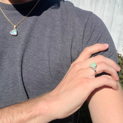 An Australian crystal opal and diamond engagement ring set in a platinum filigree mounting.  The opal plays green/blue colors and has a crack.