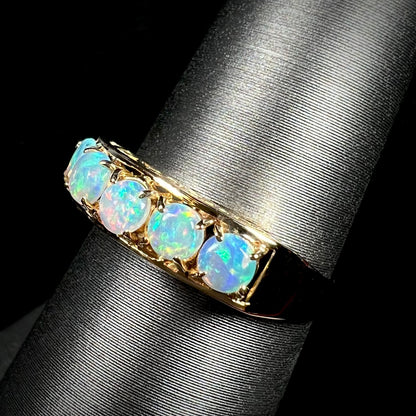 An 18 karat yellow gold line-style filigree ring mounted with five round, cabochon cut Australian crystal opals.