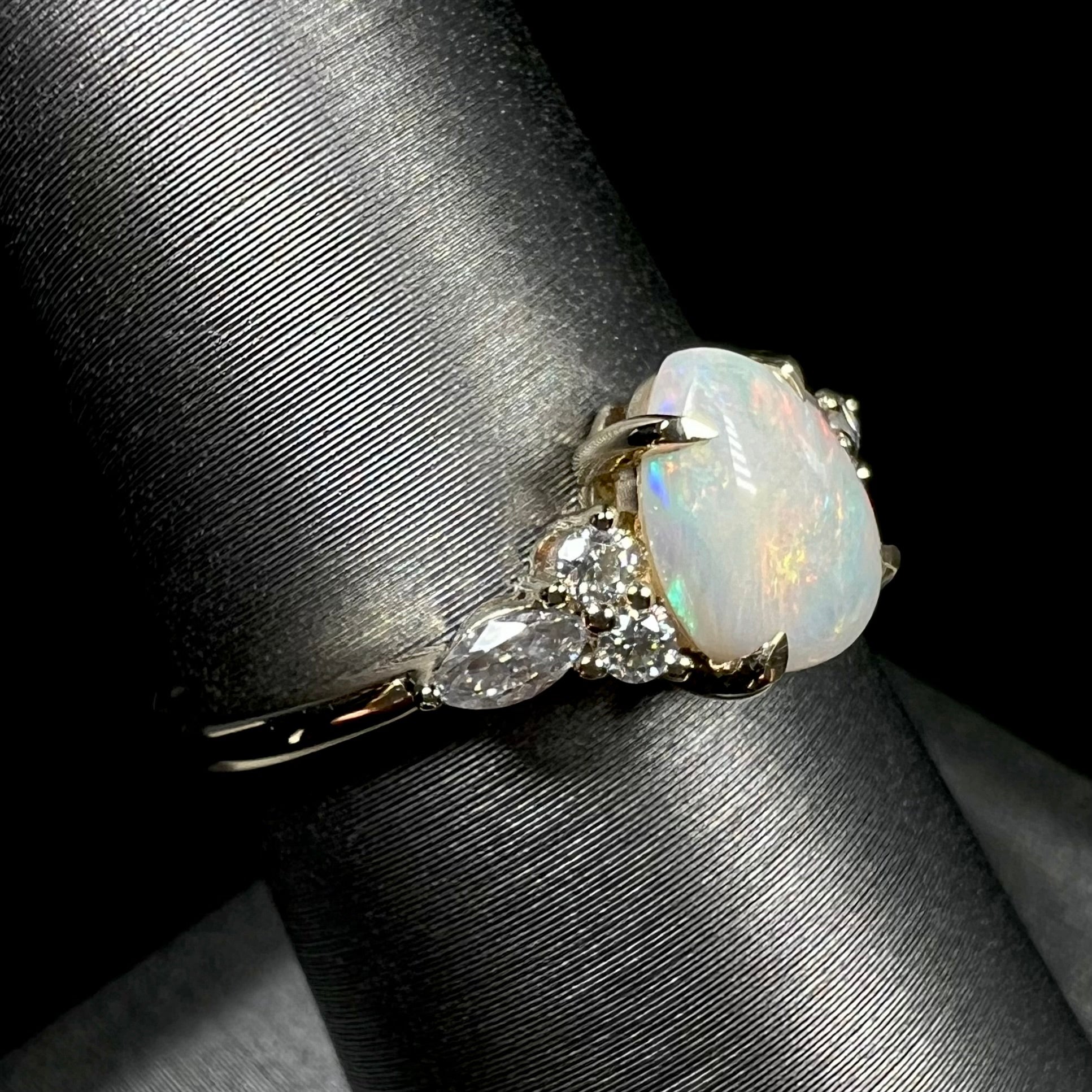 A dainty, pear shaped opal ring mounted in yellow gold with moissanite accents.