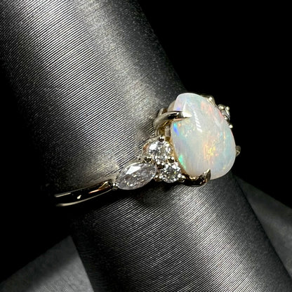 A dainty, pear shaped opal ring mounted in yellow gold with moissanite accents.