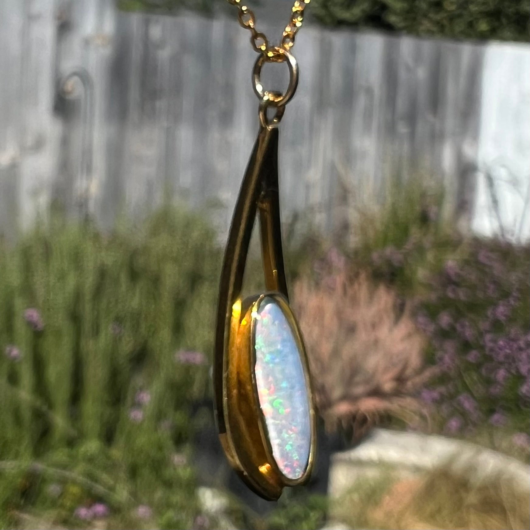 A yellow gold plated necklace set with an oval cut opal triplet.