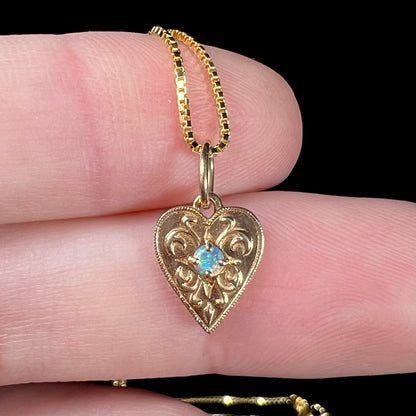 A yellow gold filigree heart necklace set with a round Australian crystal opal.  The opal has green fire.