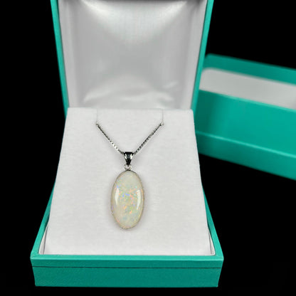 A platinum pendant mounted with an oval cut Australian white opal in a box.