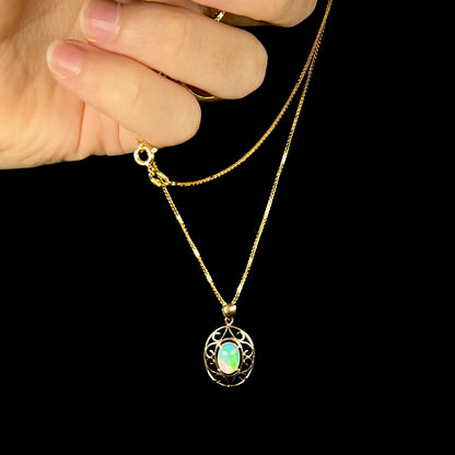 An 18 karat yellow gold filigree opal necklace.  The opal has bright green color play.