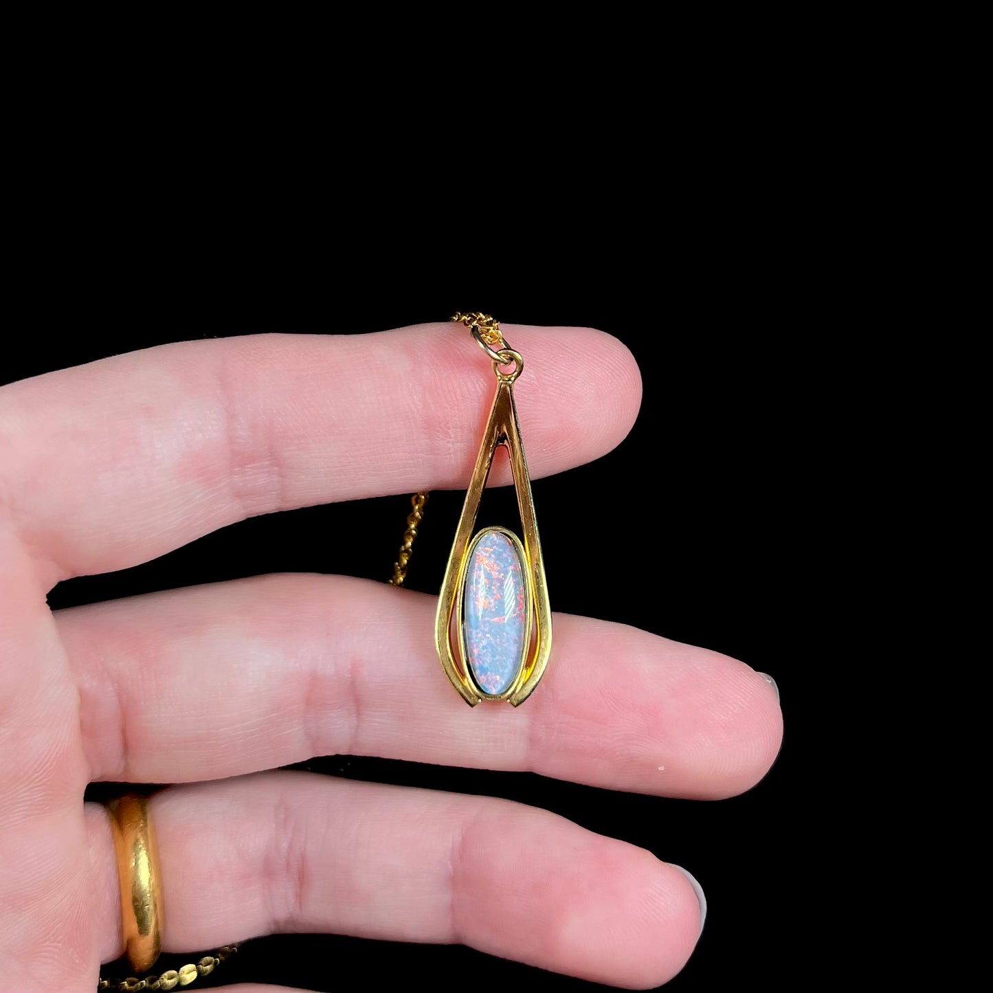 A yellow gold plated necklace set with an oval cut opal triplet.