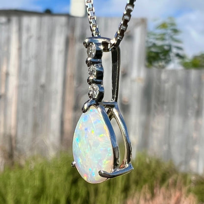 A platinum drop pendant mounted with three diamond accents and a pear shaped opal.