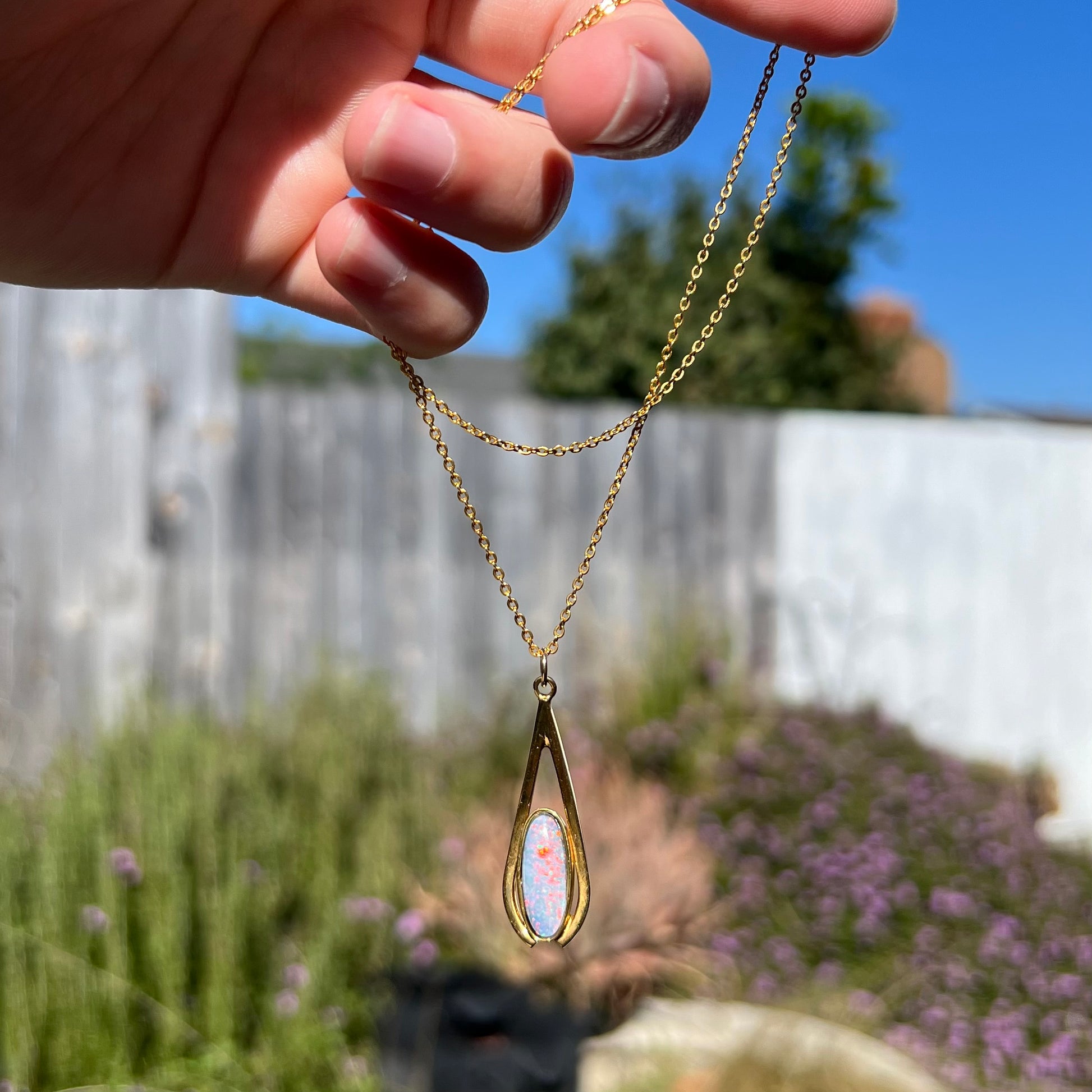 A yellow gold plated necklace set with an oval cut opal triplet.