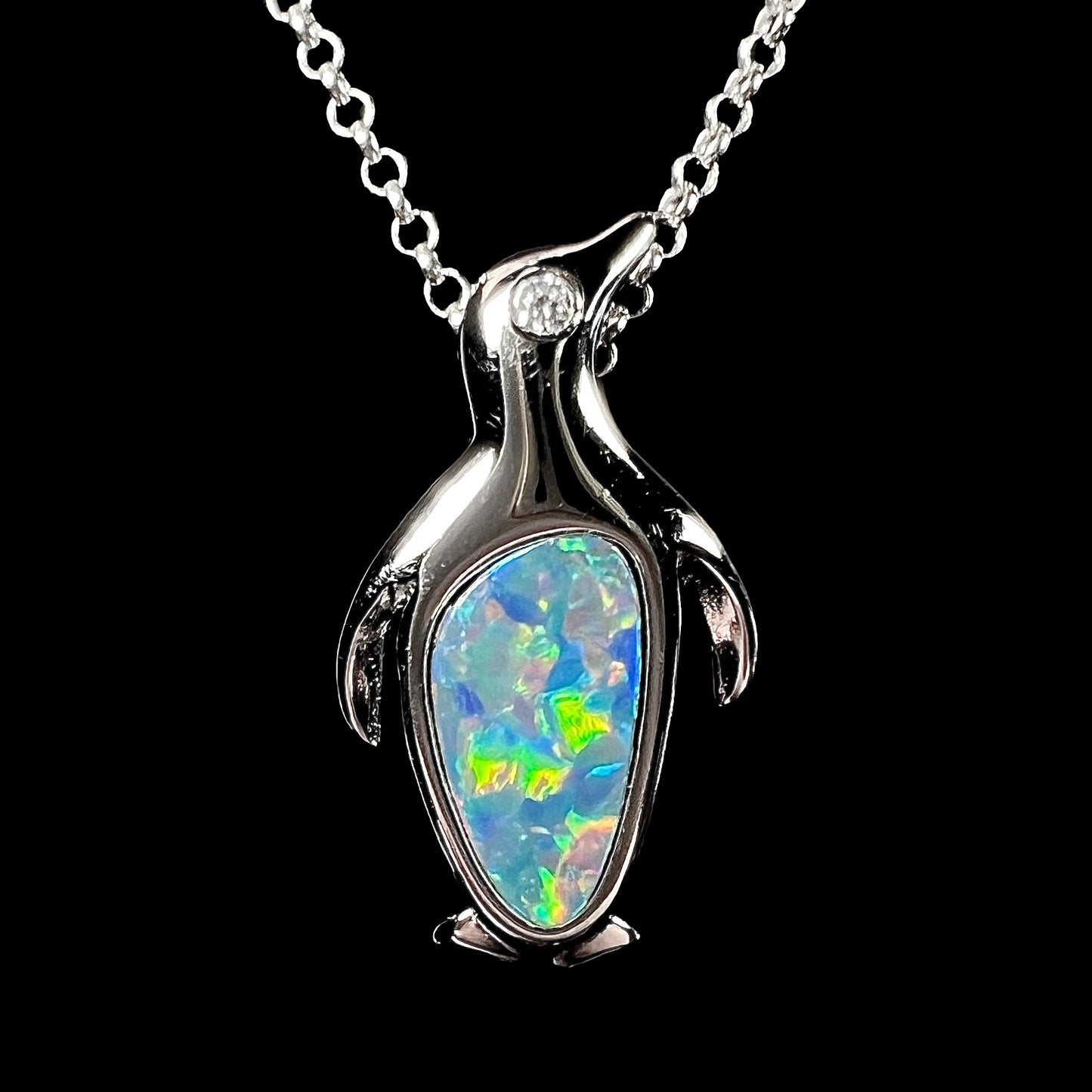 A sterling silver penguin necklace inlaid with a black opal doublet and a CZ accent in the penguin's eye.