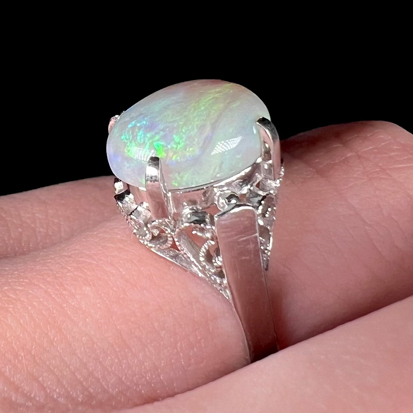 A ladies' Australian opal solitaire engagement ring mounted in platinum.  The opal has green and blue colors.