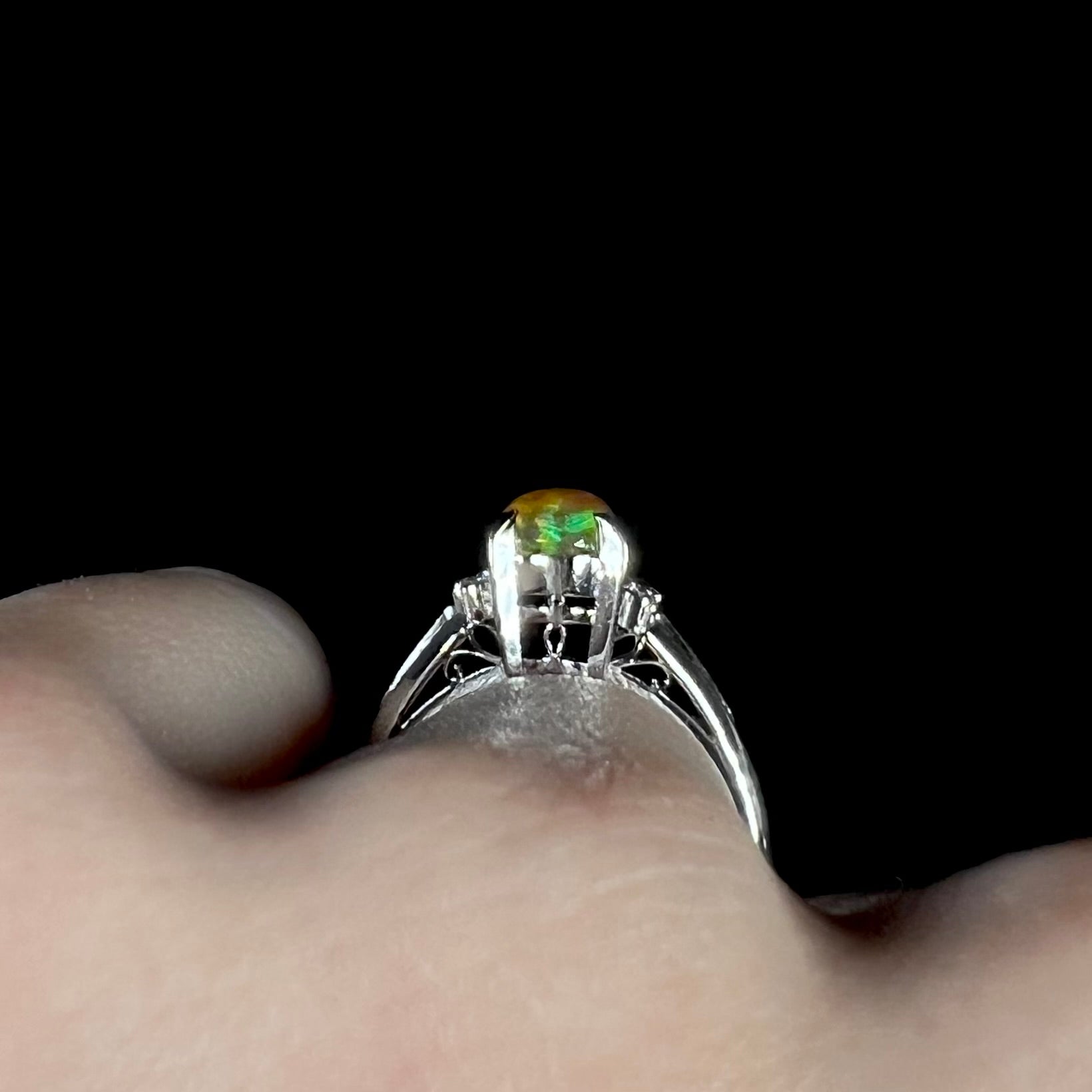 A platinum filigree and diamond-accented Mexican fire opal ring.  The opal is orange with green fire.