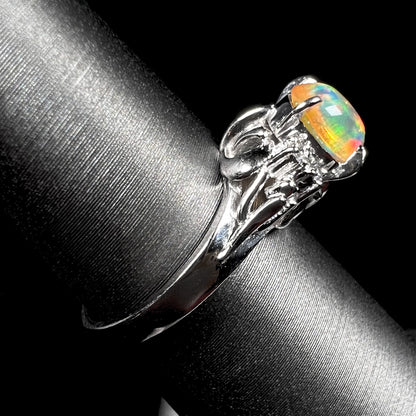 A platinum, diamond accented ring prong-set with an oval cabochon cut Mexican fire opal.