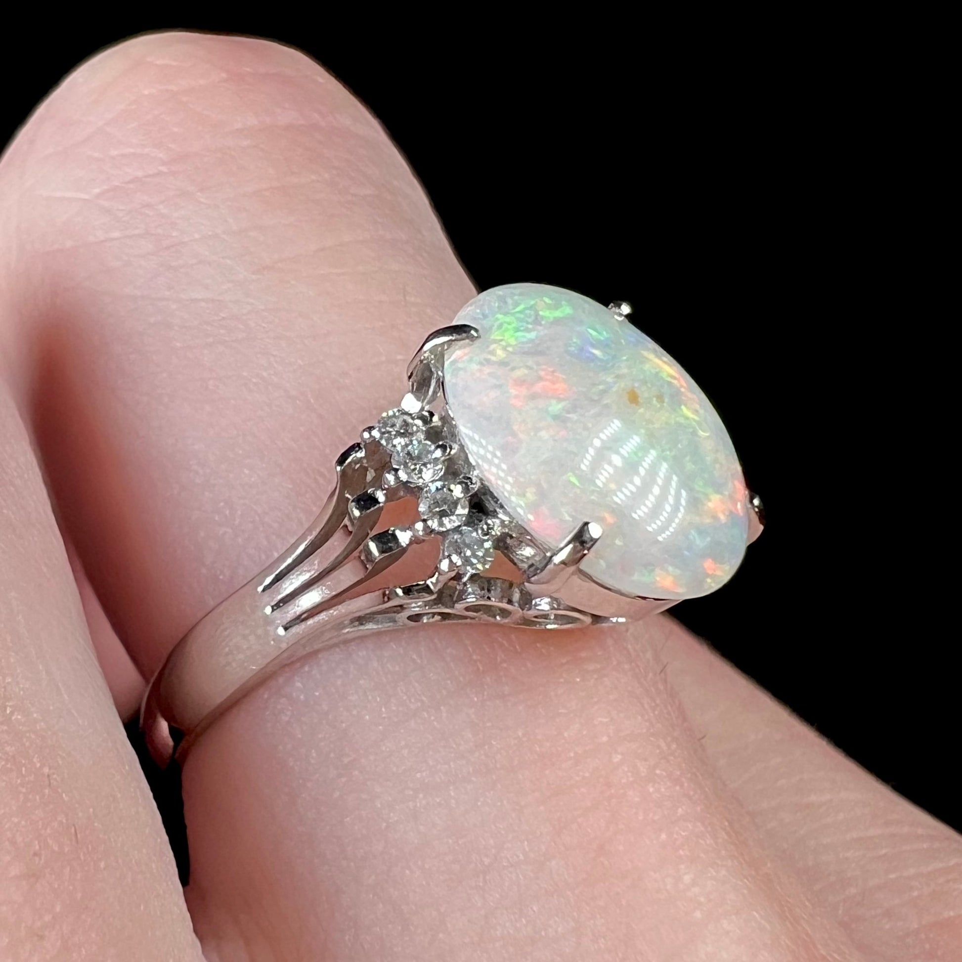 An Australian opal and diamond engagement ring in platinum.  The ring has filigree scrolling.