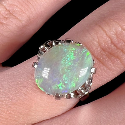 A ladies' Australian opal solitaire engagement ring mounted in platinum.  The opal has green and blue colors.