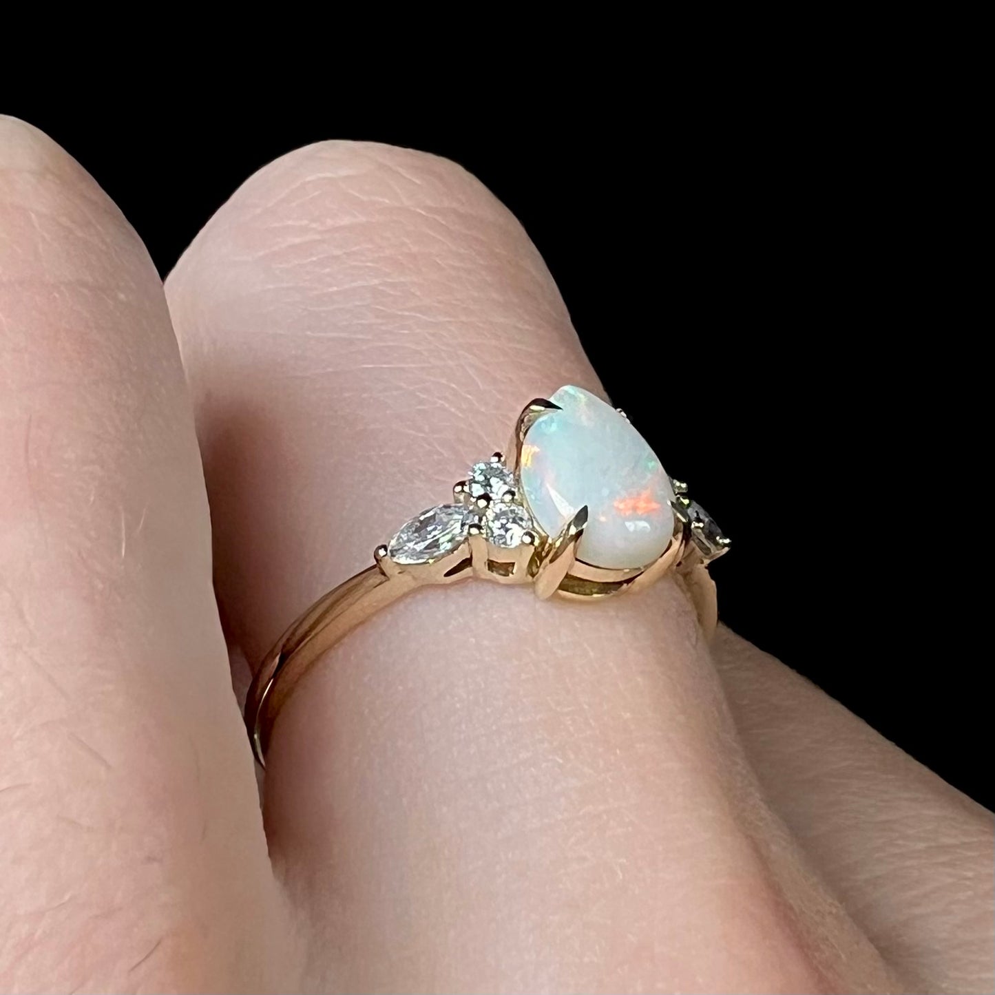 A dainty, pear shaped opal ring mounted in yellow gold with moissanite accents.