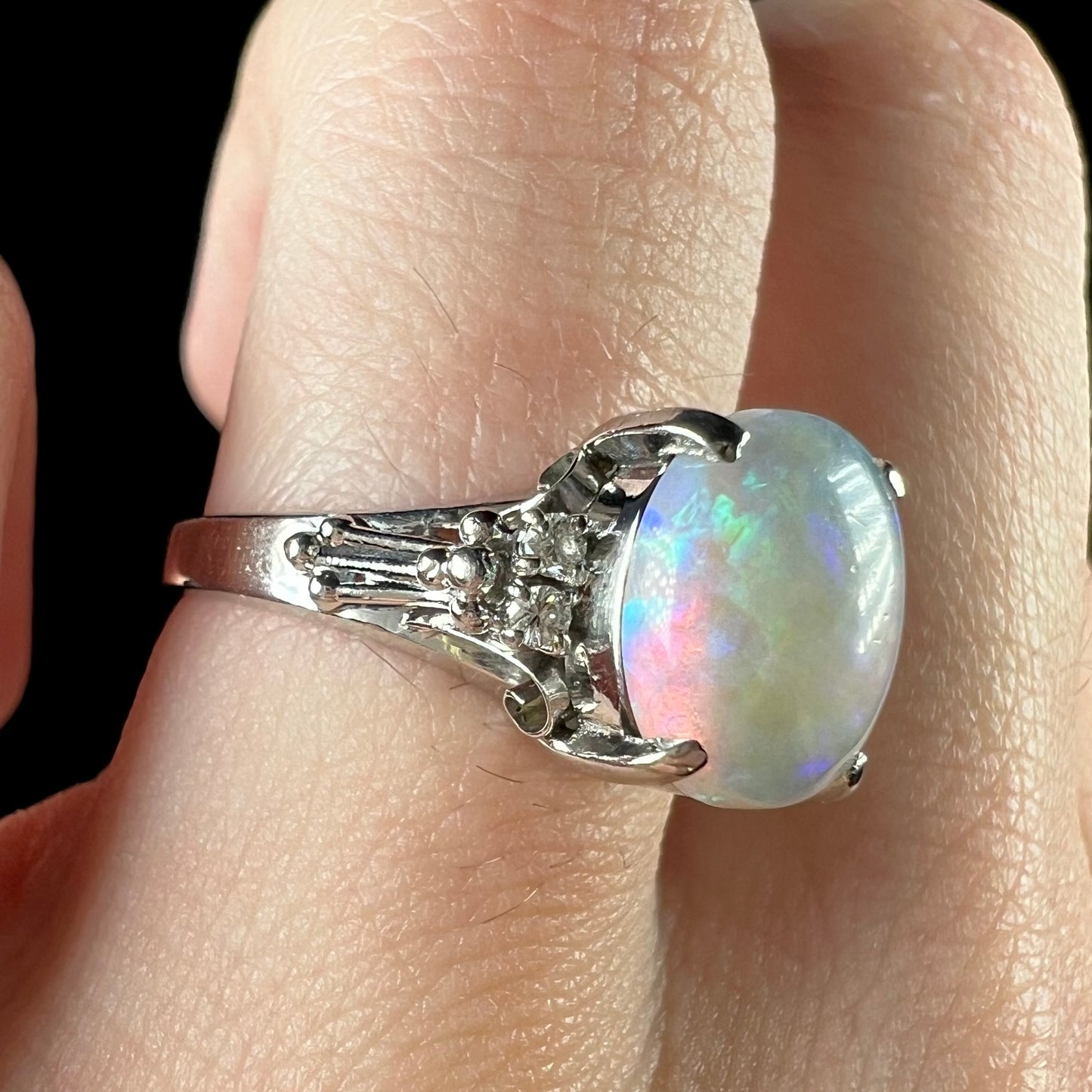 A platinum filigree ring mounted with a blue-green crystal opal and diamond accents.