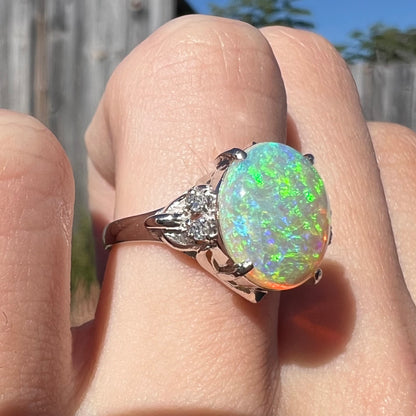 An Australian crystal opal engagement ring set with diamonds in a platinum filigree mounting.  The opal plays green/blue colors and has a crack.