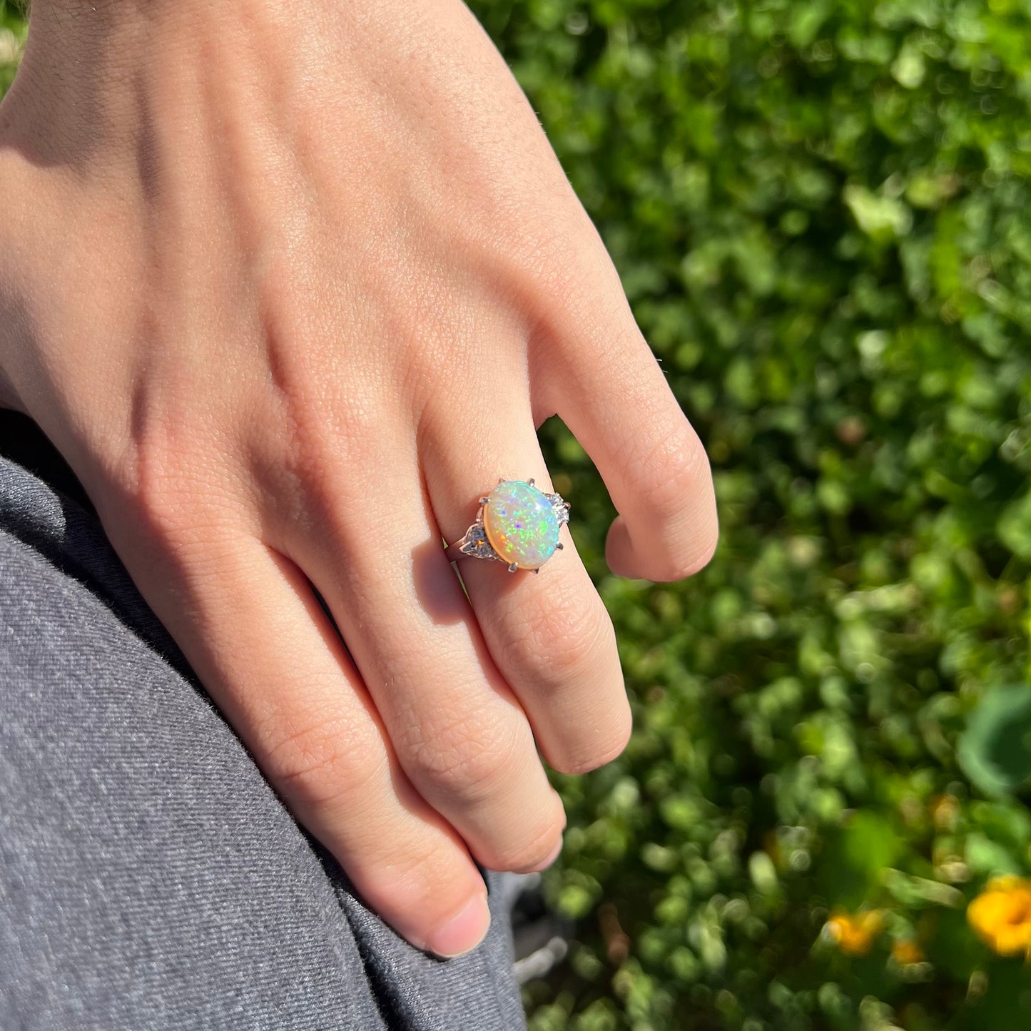 An Australian crystal opal and diamond engagement ring set in a platinum filigree mounting.  The opal plays green/blue colors and has a crack.