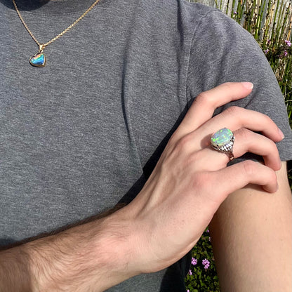 A platinum filigree ring set with a large, green-blue Mintabie crystal opal and diamonds.