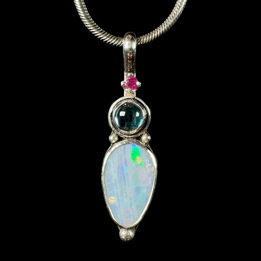 A sterling silver necklace shaped like a child, mounted with an opal doublet, a ruby, and a blue piece of glass.