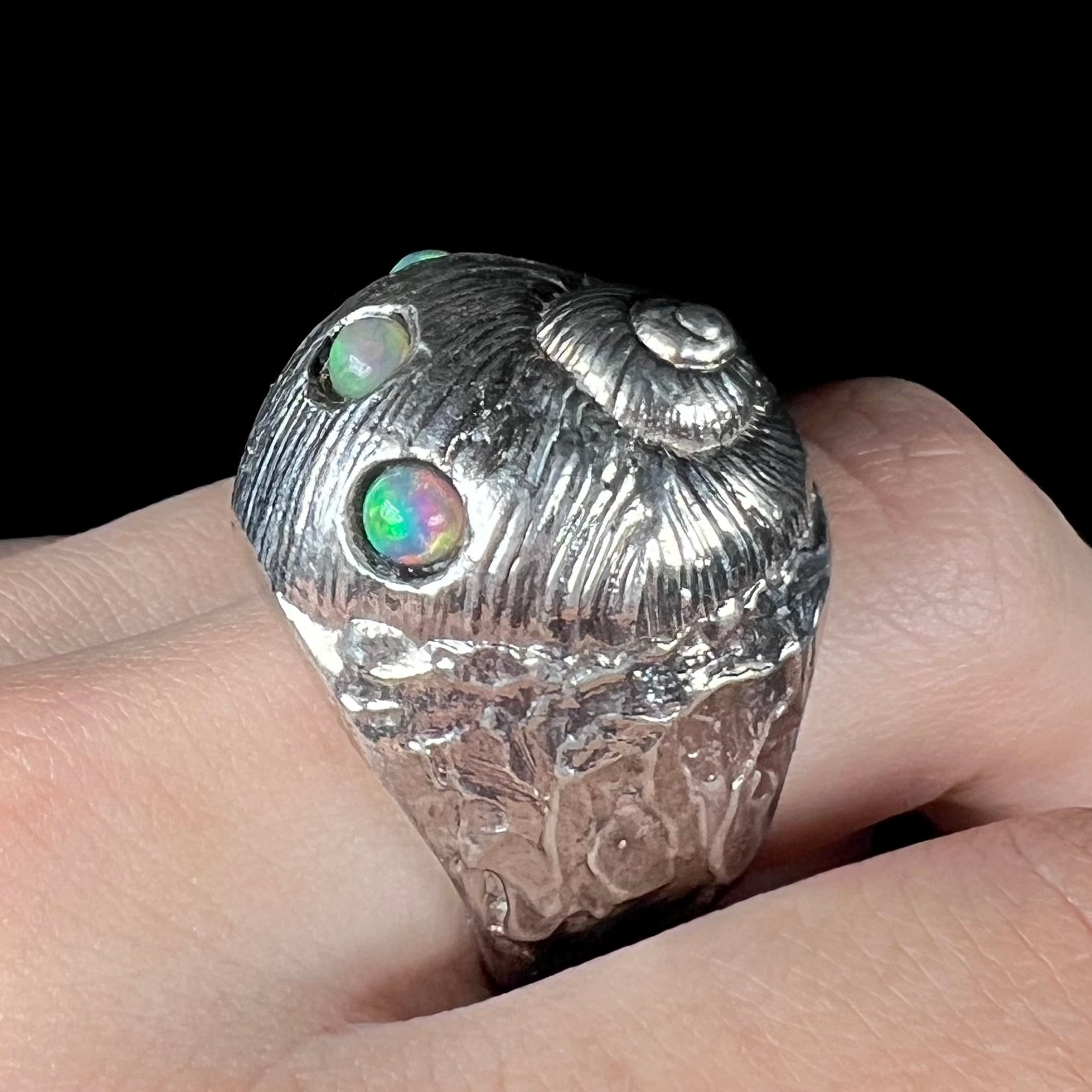 A large, three dimensional sterling silver snail seashell ring set with three round Ethiopian fire opal stones.