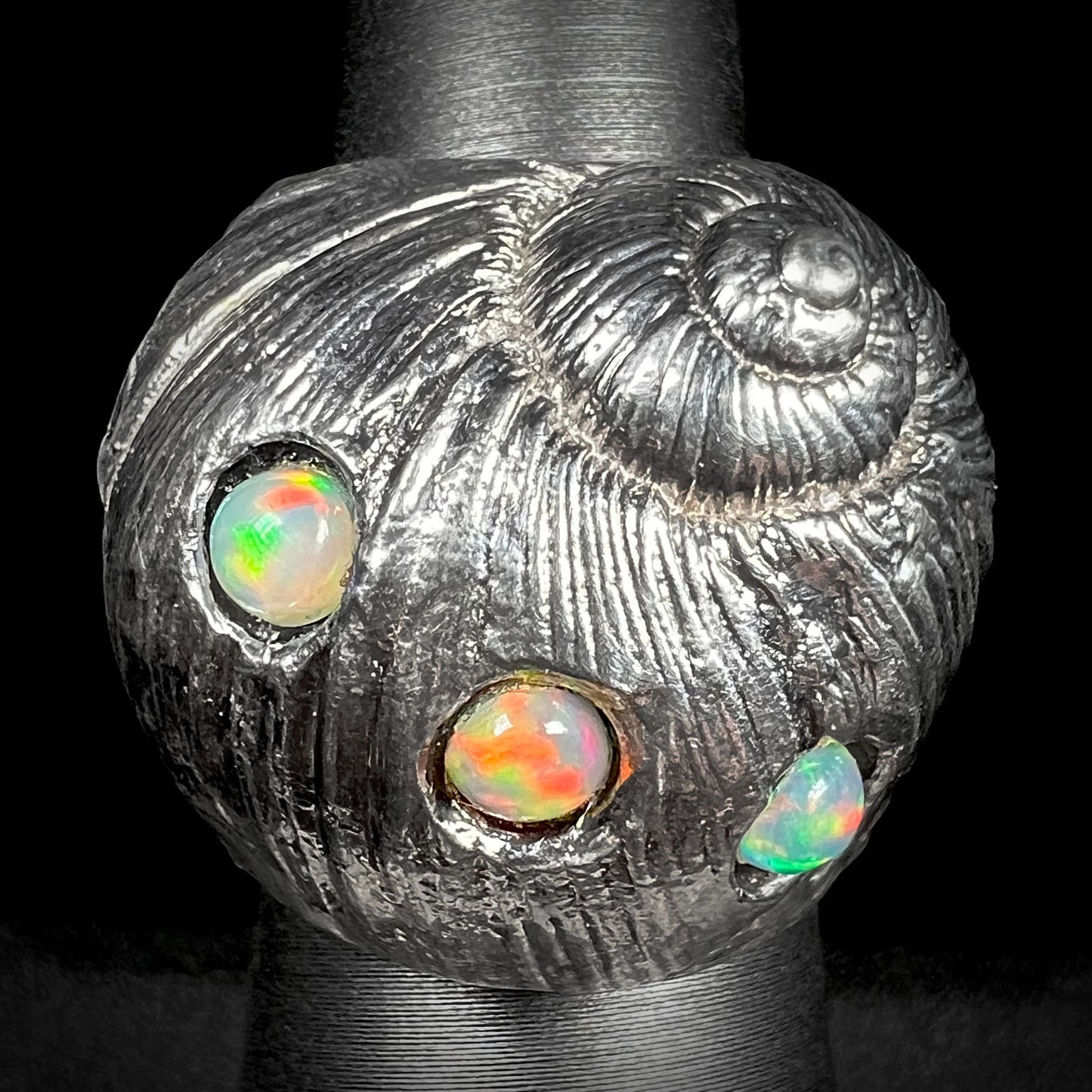 A large, three dimensional sterling silver snail seashell ring set with three round Ethiopian fire opal stones.