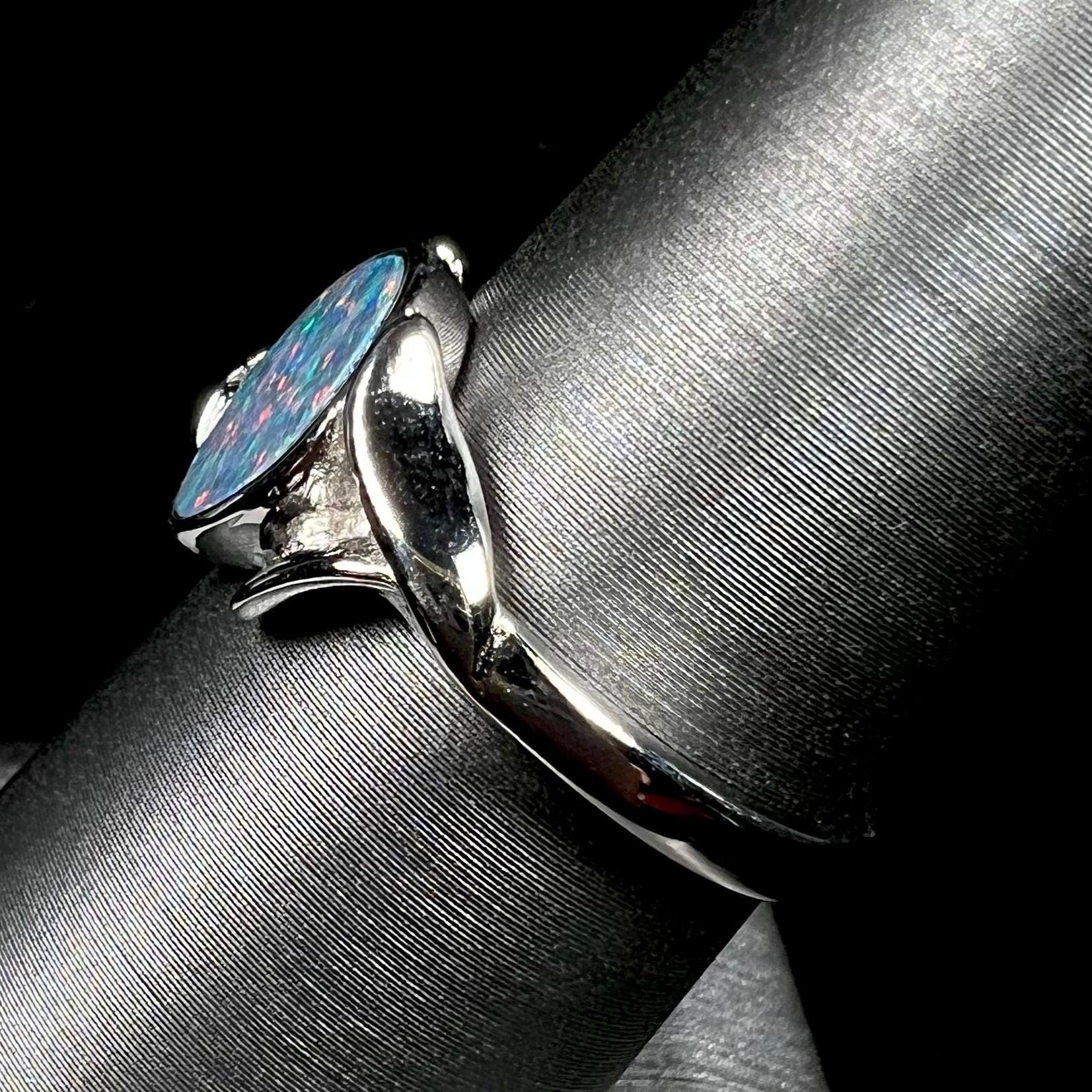 A silver leaf-style ring mounted with a multicolor black opal doublet.