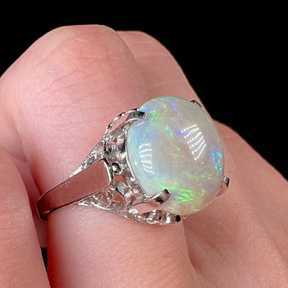 A ladies' Australian opal solitaire engagement ring mounted in platinum.  The opal has green and blue colors.