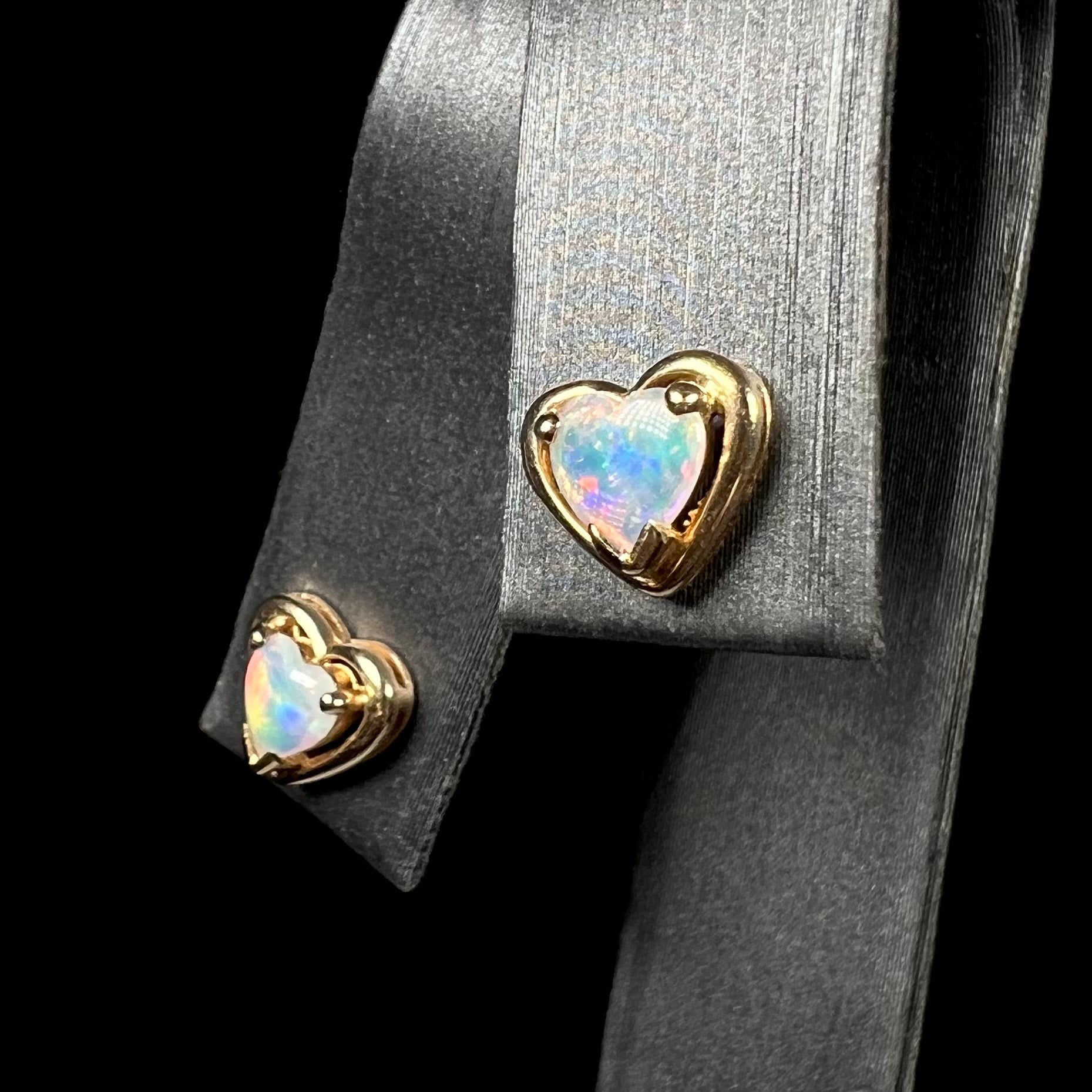 A pair of yellow gold stud earrings mounted with heart shaped natural crystal opals.