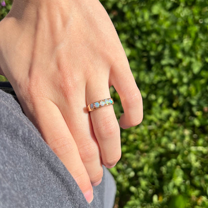 An 18 karat yellow gold line-style filigree ring mounted with five round, cabochon cut Australian crystal opals.