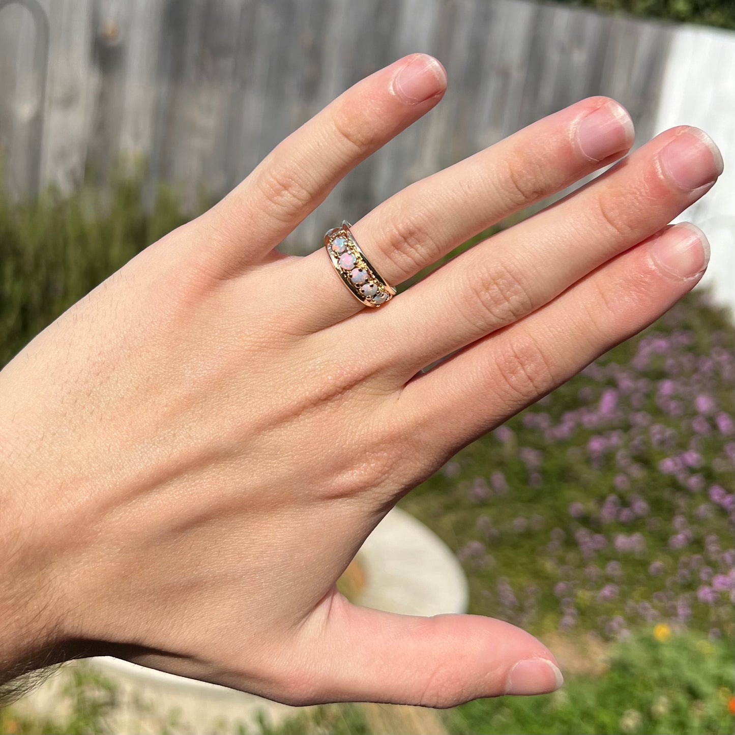 A yellow gold band set with five round cabochon cut opals and heart design accents.