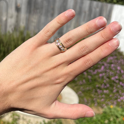 A yellow gold band set with five round cabochon cut opals and heart design accents.