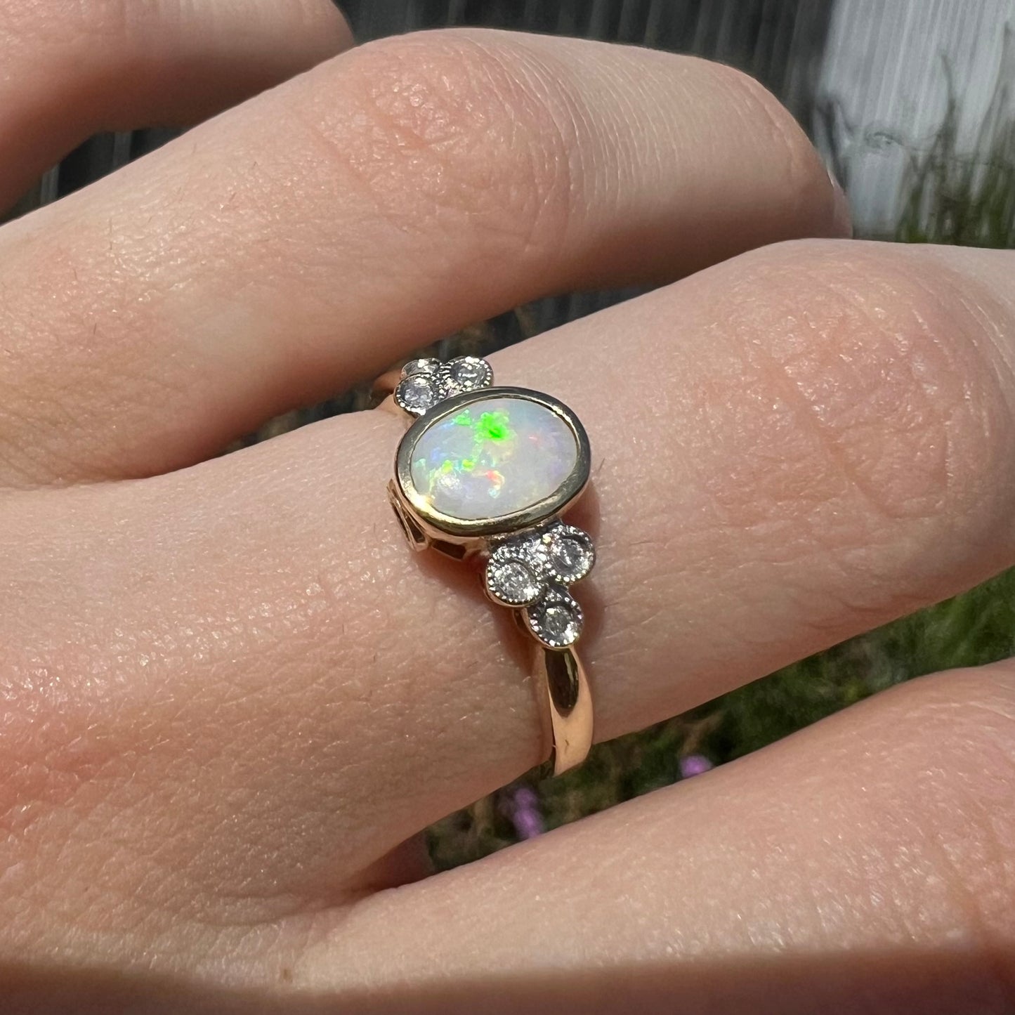 A ladies' yellow gold opal ring.  Three diamonds are set on each side of the opal.  Two rubies are set under the opal.