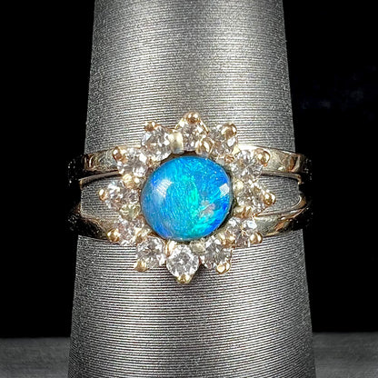 A ladies' round cut black opal and diamond halo ring.  The ring is yellow gold and has a split shank.