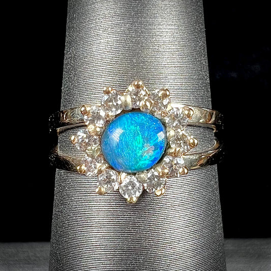 A ladies' round cut black opal and diamond halo ring.  The ring is yellow gold and has a split shank.