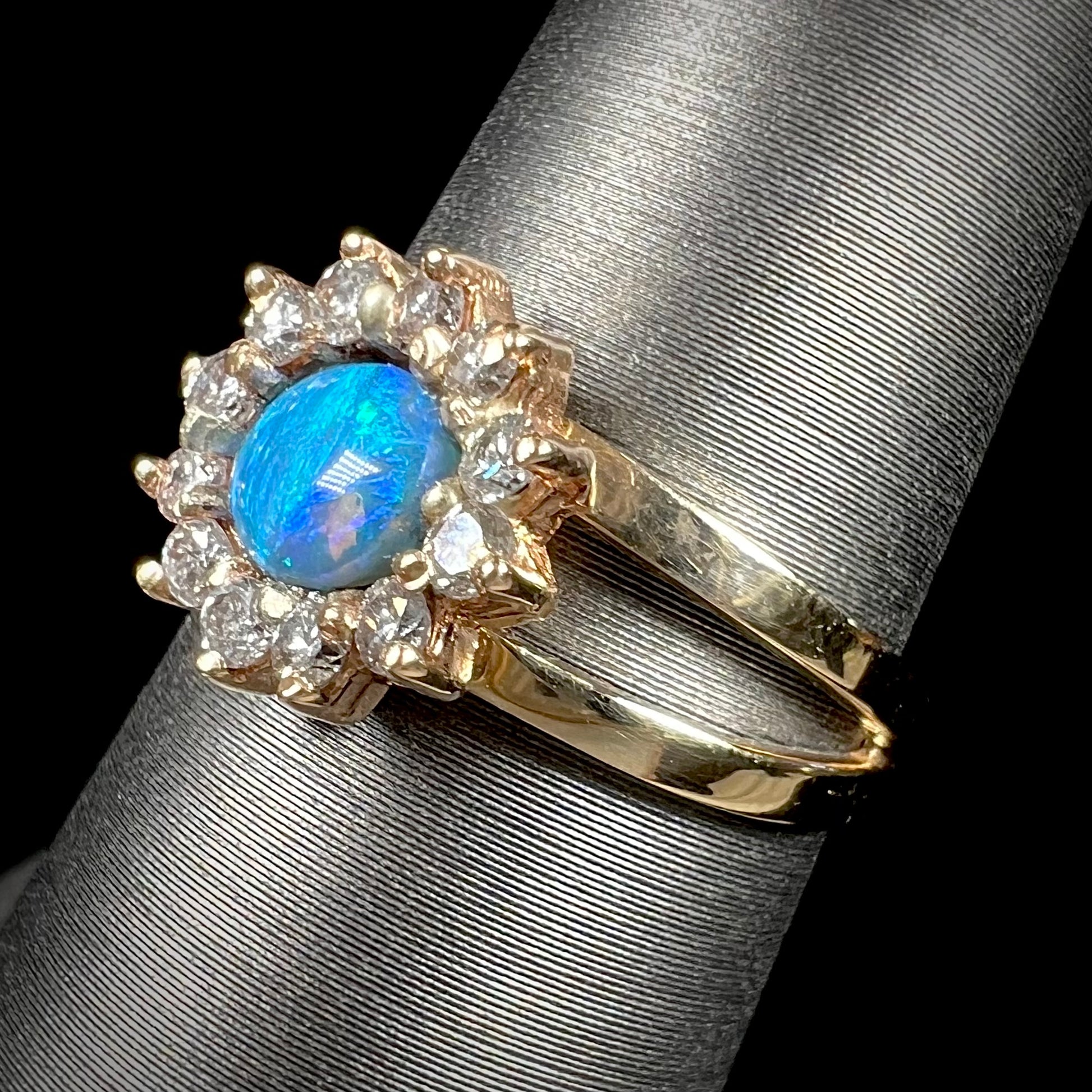 A ladies' round cut black opal and diamond halo ring.  The ring is yellow gold and has a split shank.