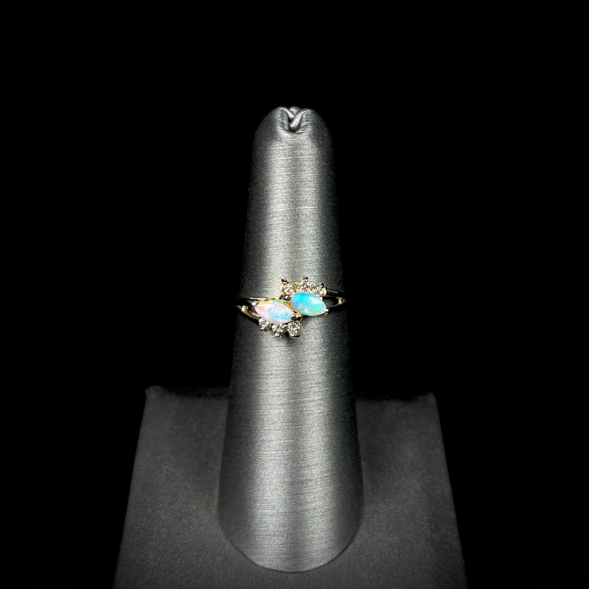 A yellow gold ring mounted with two marquise cut opals and accented with six round diamonds.