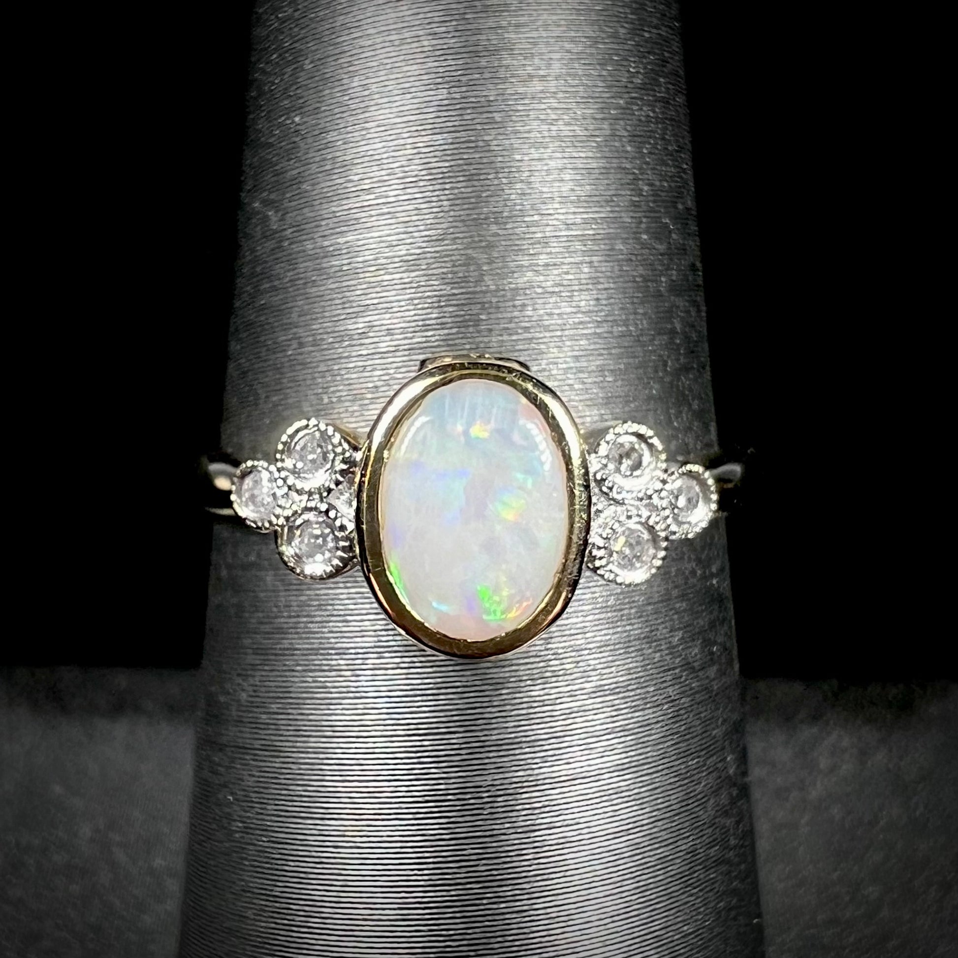 A ladies' yellow gold opal ring.  Three diamonds are set on each side of the opal.  Two rubies are set under the opal.