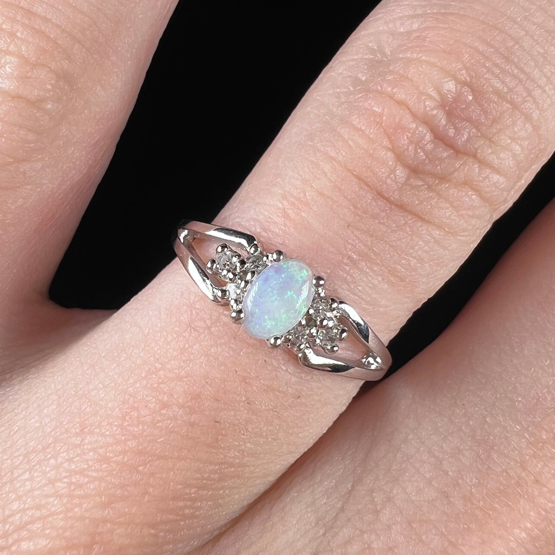 A ladies' white gold opal ring mounted with round diamond accents.