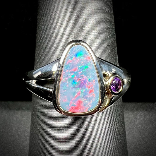 A two-tone sterling silver and yellow gold ring set with a black opal doublet and an amethyst accent.