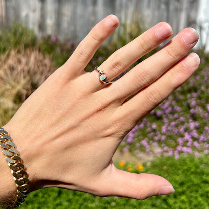 An oval cabochon cut opal and diamond engagement ring in yellow gold.