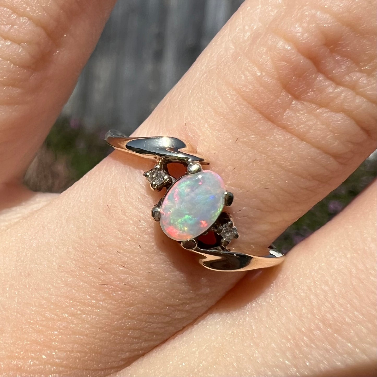 An oval cabochon cut opal and diamond engagement ring in yellow gold.