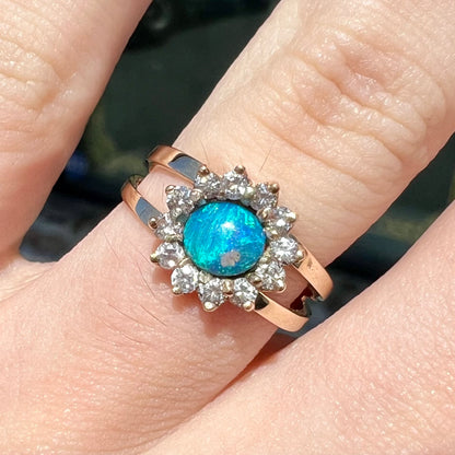 A ladies' round cut black opal and diamond halo ring.  The ring is yellow gold and has a split shank.