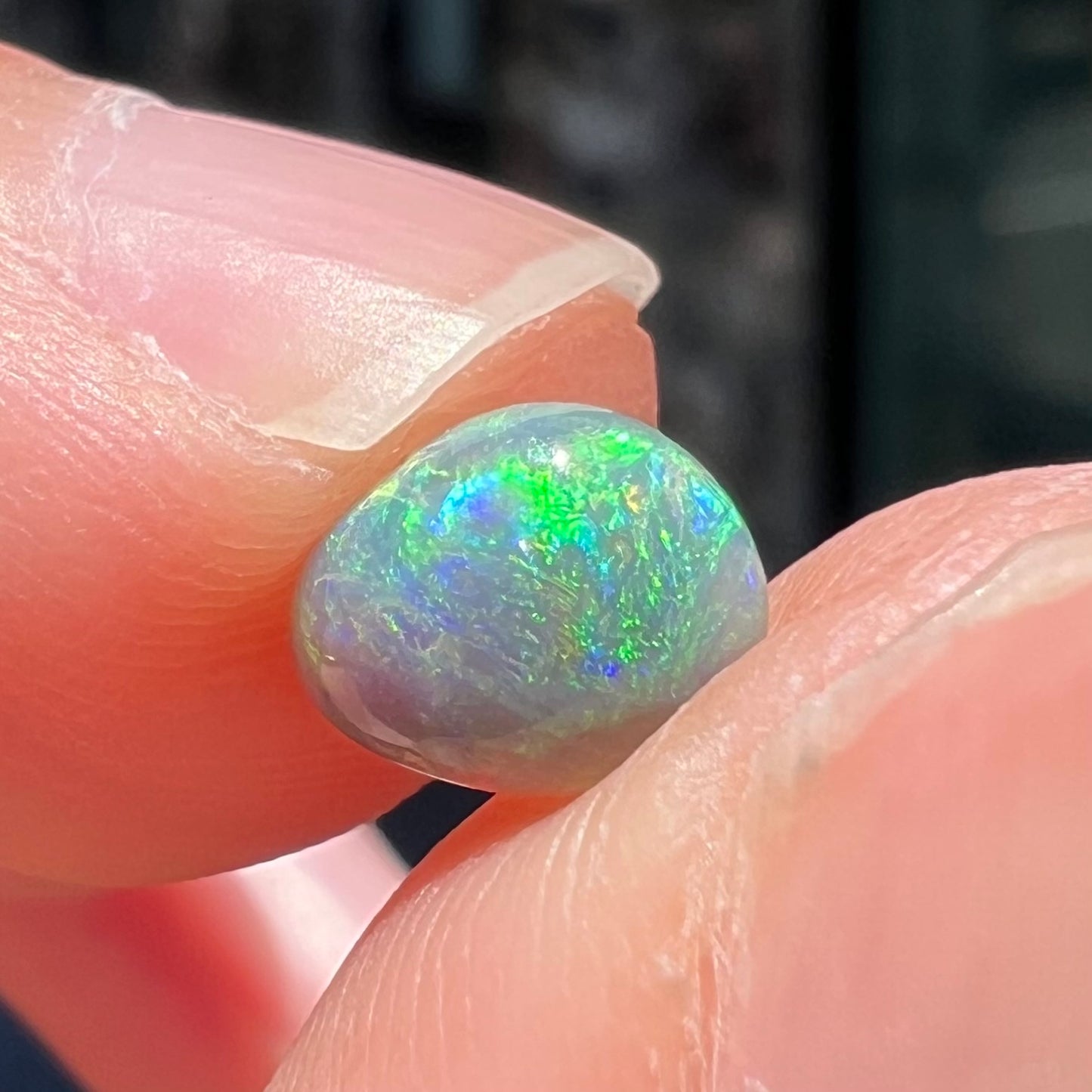 A loose, freeform shaped semi-black opal stone from Lightning Ridge, Australia.