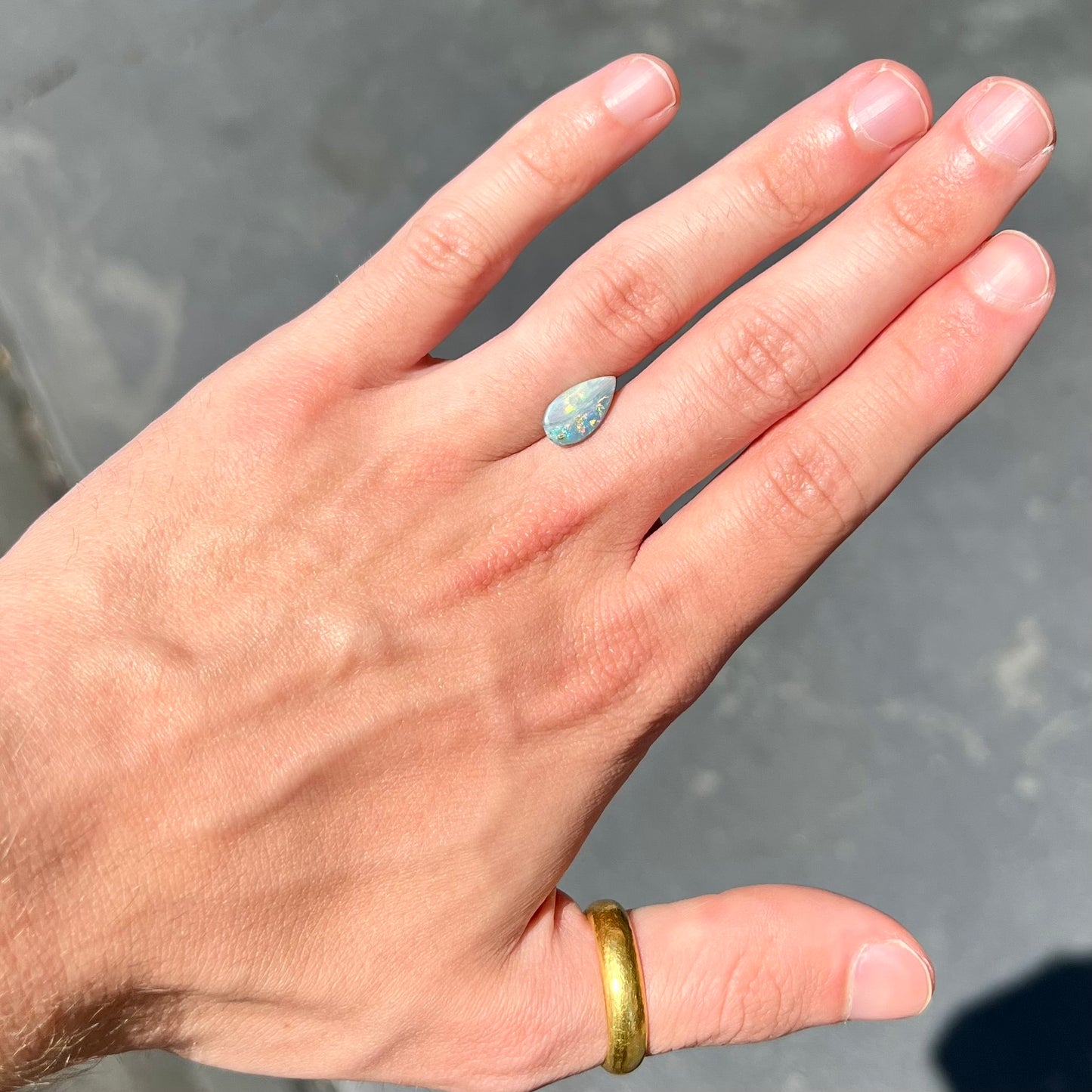 A loose, pear shaped Australian opal stone.  The opal shows green and blue colors.