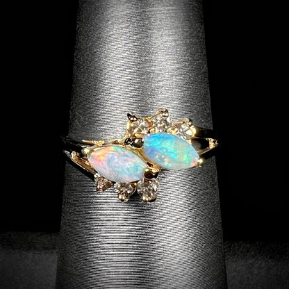 A yellow gold ring mounted with two marquise cut opals and accented with six round diamonds.