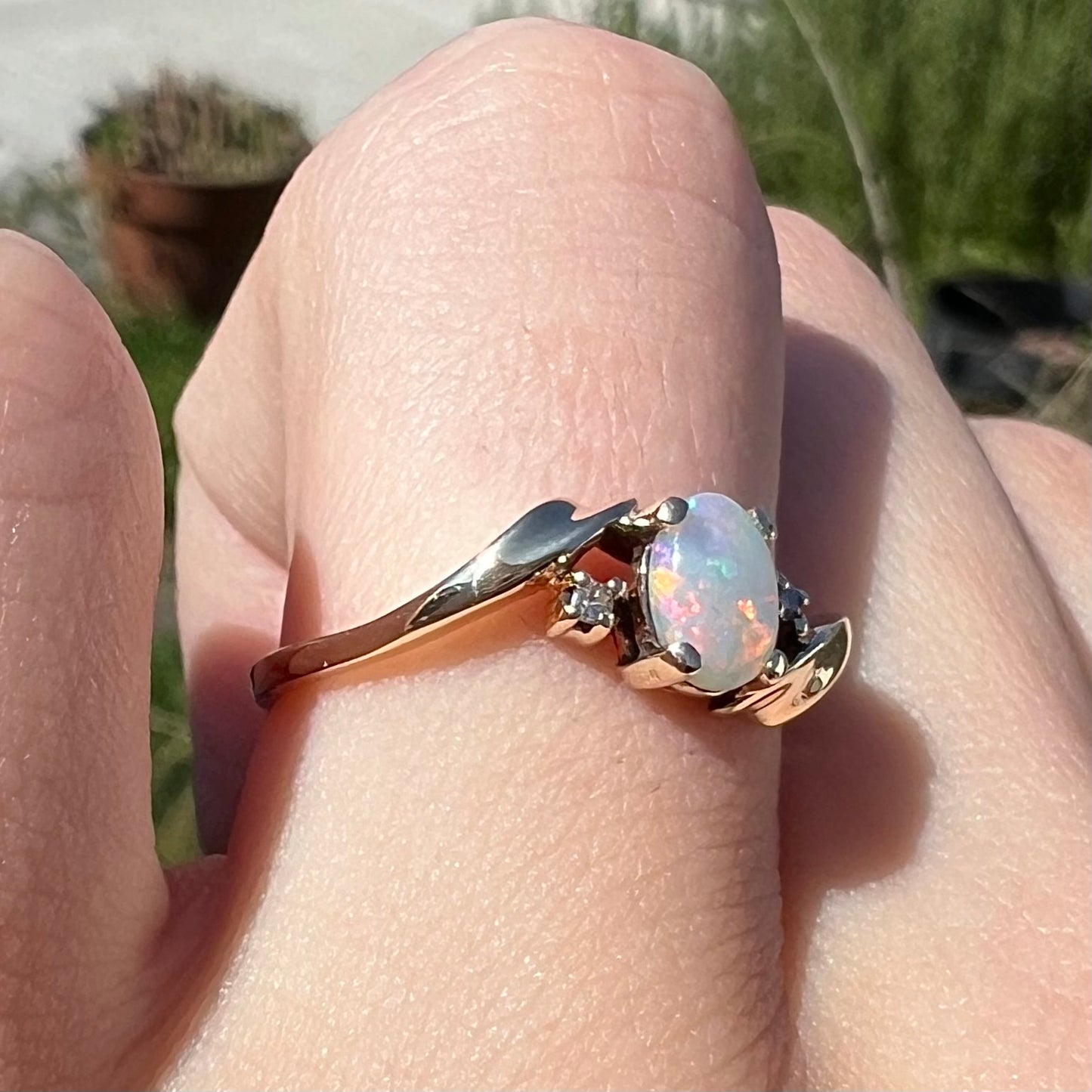 An oval cabochon cut opal and diamond engagement ring in yellow gold.