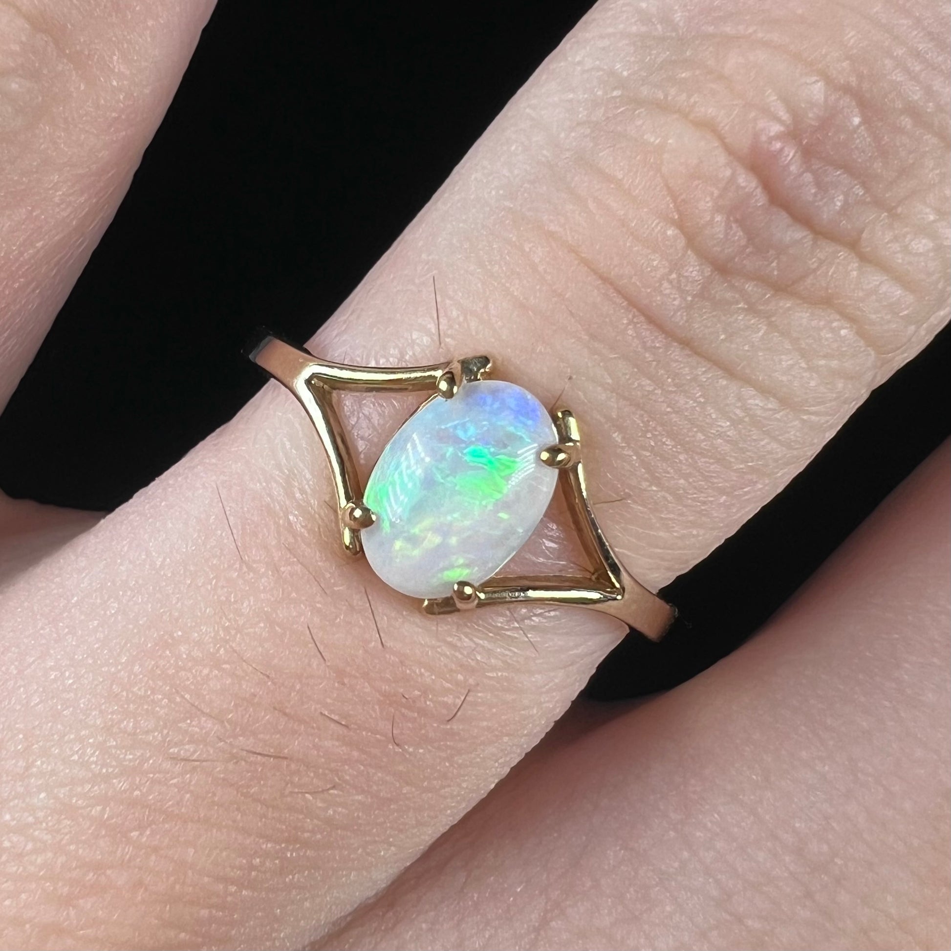 A ladies' simple opal solitaire ring.  The ring is yellow gold with a split shank.