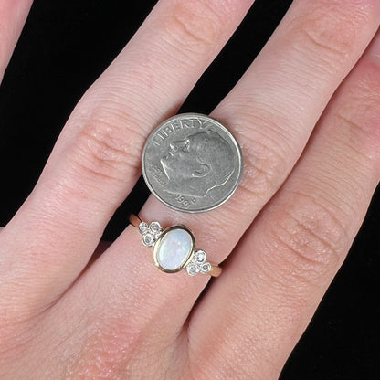 A ladies' yellow gold opal ring.  Three diamonds are set on each side of the opal.  Two rubies are set under the opal.