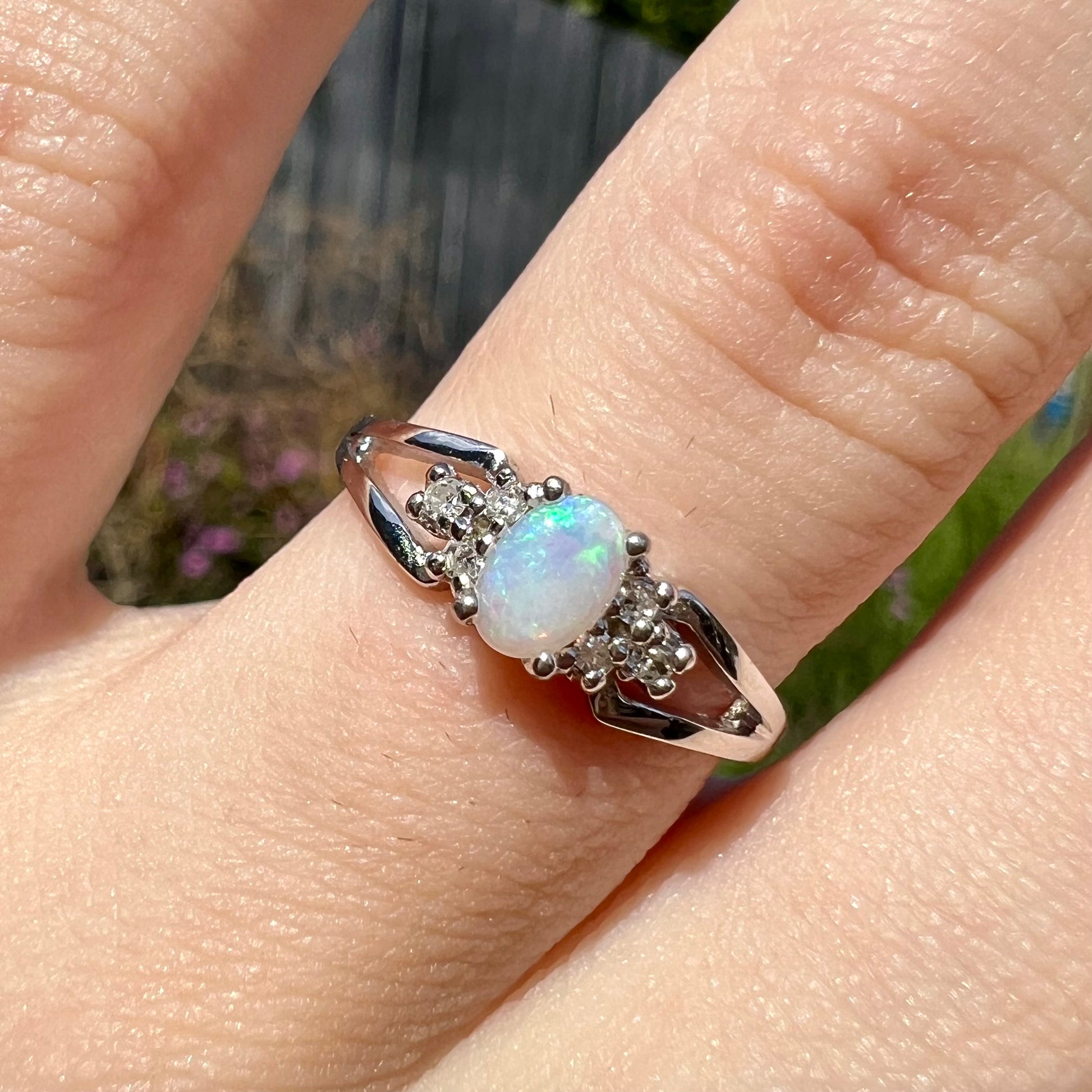 A ladies' white gold opal ring mounted with round diamond accents.